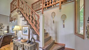 A staircase with wooden railings, a desk with a lamp, a chair, and two tennis rackets on the wall.
