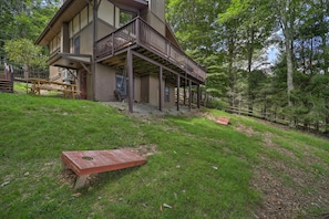 A two-story house with a balcony, surrounded by a wooded area.