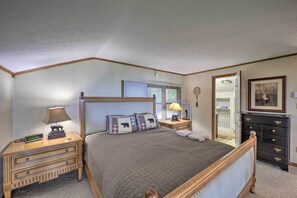 Een slaapkamer met een houten bed, nachtkastjes, een dressoir en een spiegel.