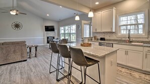 Una cocina moderna con armarios blancos, encimera de granito y una isla central con taburetes de bar.