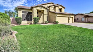 A two-story house with a garage, a well-maintained lawn, and a clear blue sky.