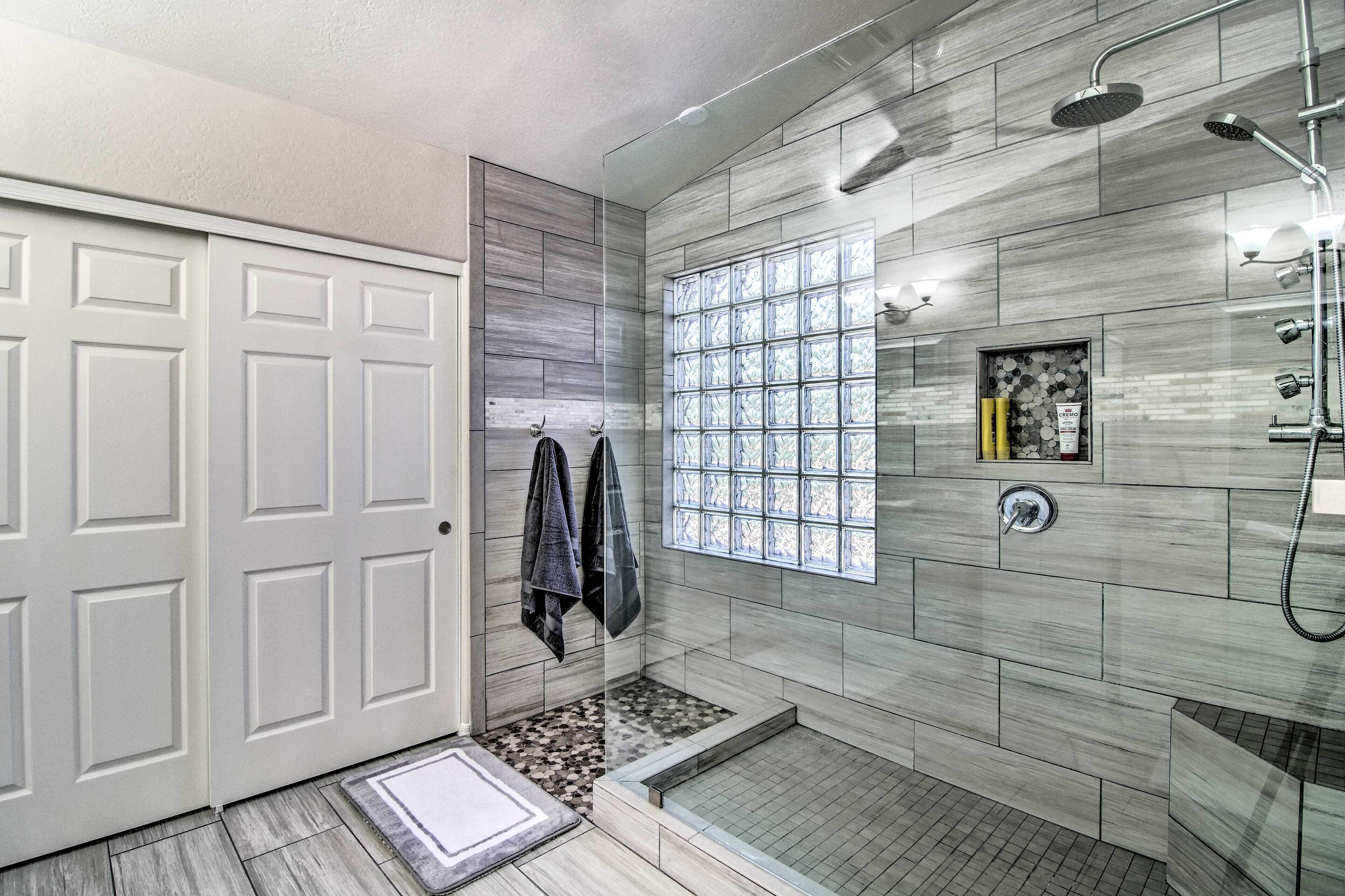 A modern bathroom with a shower, a glass block window, and a tiled floor.
