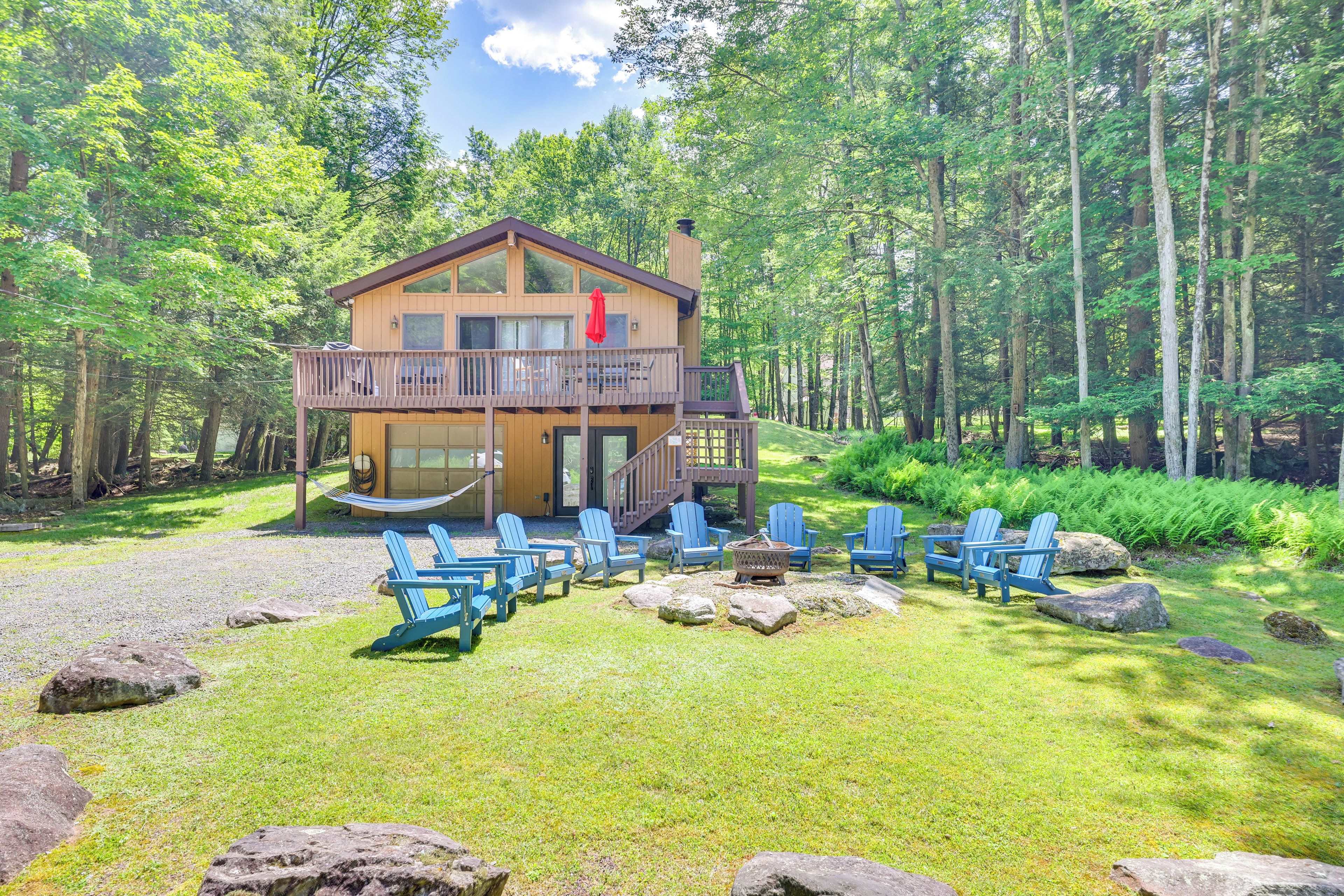 A lodge with a deck, outdoor seating, and a forest backdrop.