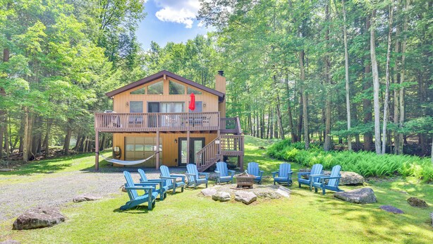 A lodge with a deck, outdoor seating, and a forest backdrop. - Secluded Family Cabin w/ Fire Pit in Lake Ariel! (Lake Ariel)