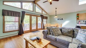 A spacious living room with a wooden floor, a sofa with patterned cushions, a wooden coffee table, and a ceiling fan. - Secluded Family Cabin w/ Fire Pit in Lake Ariel! (Lake Ariel)