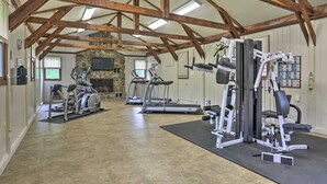 A spacious gym with treadmills, weight machines, and a stone fireplace. - Secluded Family Cabin w/ Fire Pit in Lake Ariel! (Lake Ariel)