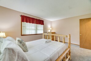 Un dormitorio con cama, mesita de noche, lámpara y cabecero de madera.