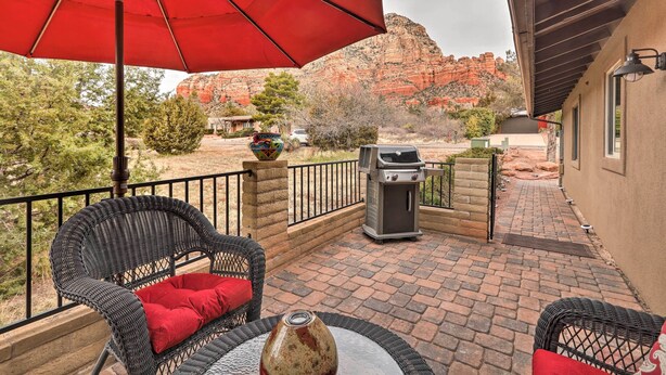 A patio with wicker furniture, a red umbrella, and a barbecue grill. - Walk to Trails! Sedona Casita w/ Fire Pit & Views (Sedona)