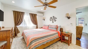 A bedroom with a bed, a ceiling fan, a nightstand, a lamp, a dresser, and a door leading to another room. - Walk to Trails! Sedona Casita w/ Fire Pit & Views (Sedona)