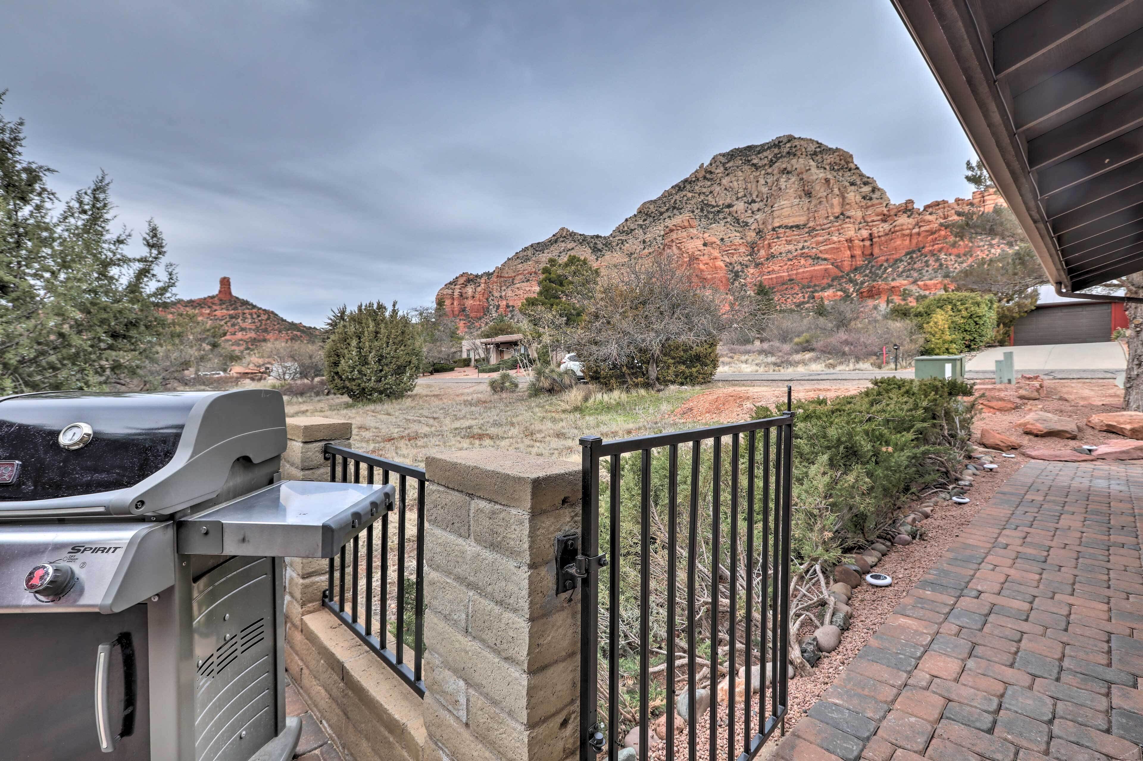Une terrasse avec un barbecue, un mur en pierre et une vue sur des formations rocheuses rouges.