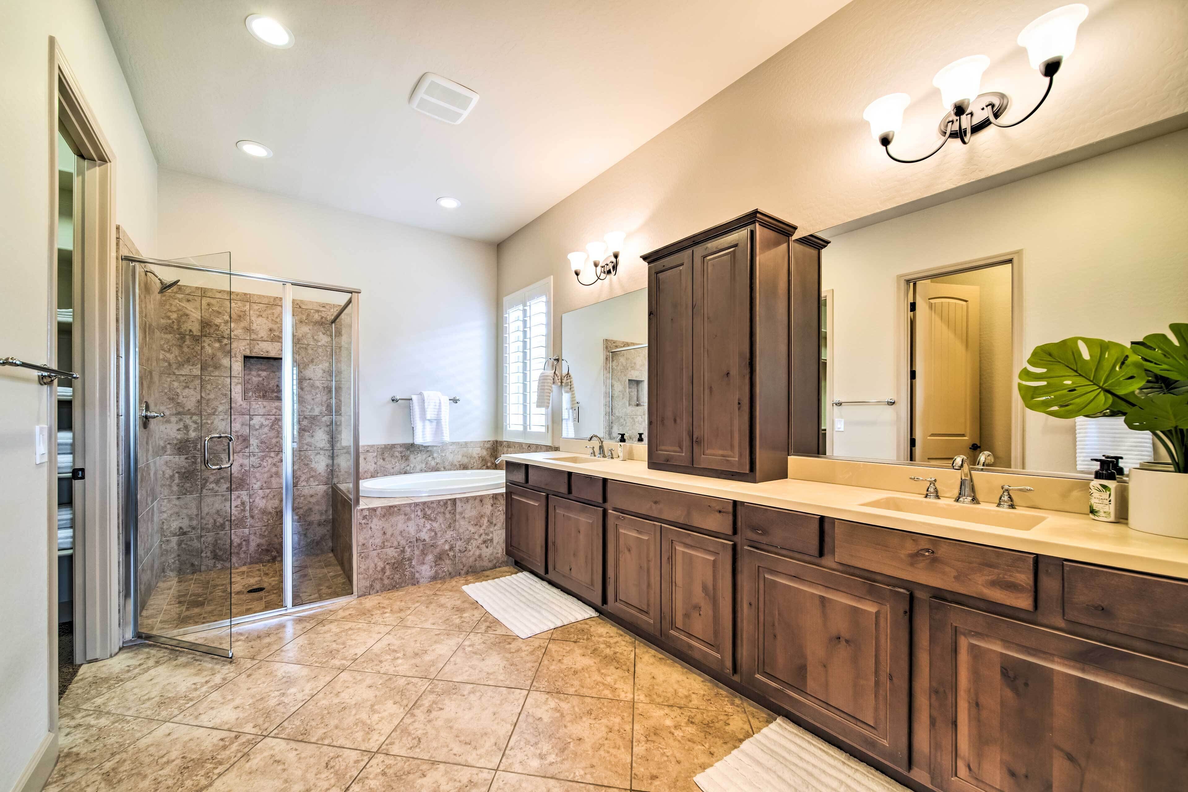 A modern bathroom with a walk-in shower, a large vanity with dark wood cabinets, and a large mirror.