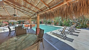 Un espace extérieur abrité comprenant une piscine, des chaises longues et une table avec des chaises.