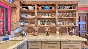 A kitchen with wooden shelves, a granite countertop, and a sink.