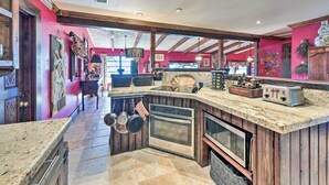 A kitchen with a stone countertop, wooden cabinets, and stainless steel appliances.