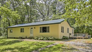 A yellow single-story house with a green roof, surrounded by trees and a well-maintained lawn. - Jasonville Cabin - Walk to Shakamak State Park! (Jasonville)