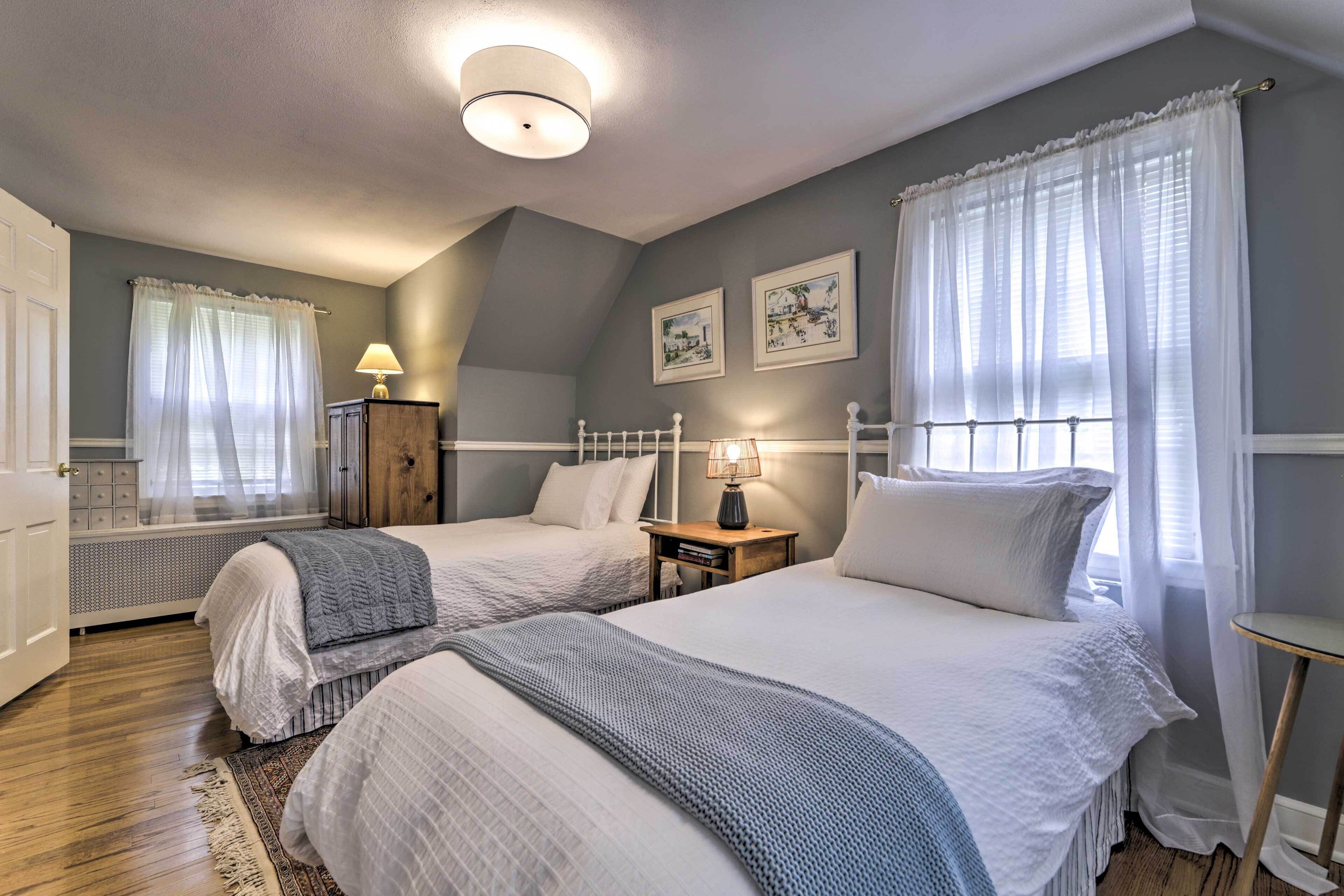 Ein Schlafzimmer mit zwei Betten, einem Nachttisch mit Lampe, einem Heizkörper und gerahmten Bildern an der Wand.