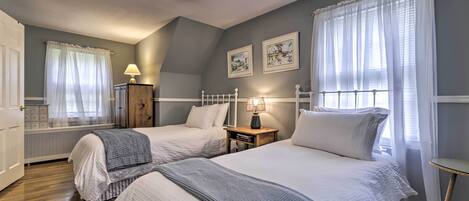 Ein Schlafzimmer mit zwei Betten, einem Nachttisch mit Lampe, einem Heizkörper und gerahmten Bildern an der Wand.