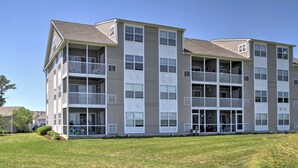 A multi-story residential building with balconies, large windows, and a grassy lawn. - Near Beaches: Ocean View Condo w/ Balcony! (Ocean View)