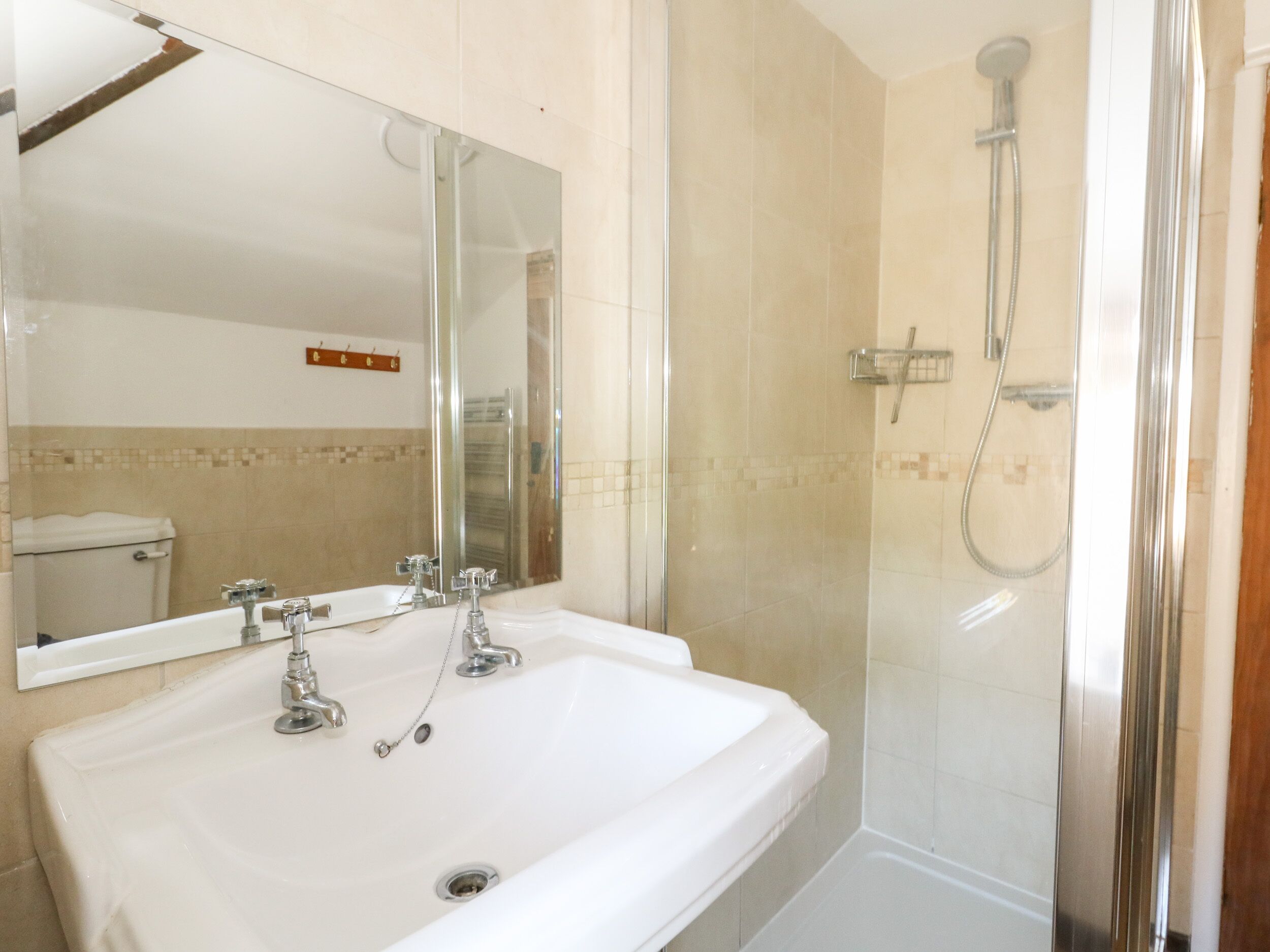 A bathroom with a white sink, a mirror, and a shower enclosure.