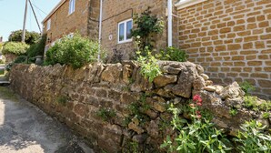Un edificio in pietra con un muro di pietra e un vialetto lastricato.
