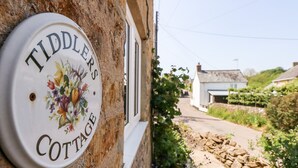 Un cartello su un muro di pietra con la scritta 'Tiddlers Cottage'.