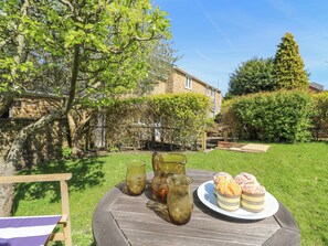 A round wooden table with a plate of cupcakes and two glasses on a grassy lawn. - Tiddlers Cottage (Bridport)