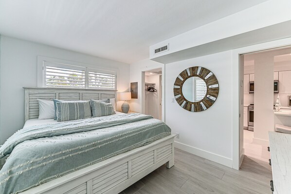 Een slaapkamer met een bed, een ronde spiegel en uitzicht op de badkamer.