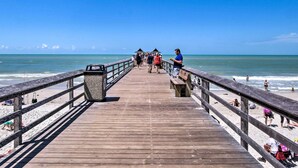 A wooden pier leading to a beach with clear skies. - Coastal Downtown Naples Condo - Walk to the Beach! (Naples)
