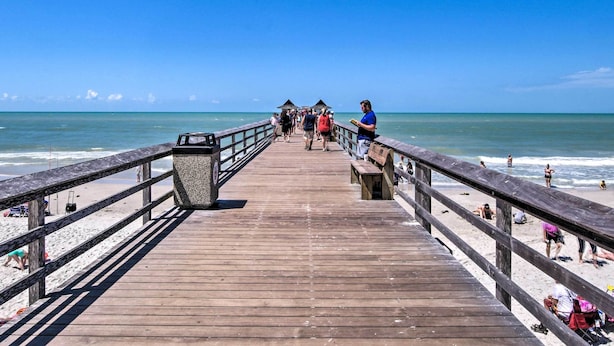 A wooden pier leading to a beach with clear skies. - Coastal Downtown Naples Condo - Walk to the Beach! (Naples)