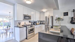 Een moderne keuken met witte kasten, roestvrijstalen apparatuur en een zwart aanrecht.