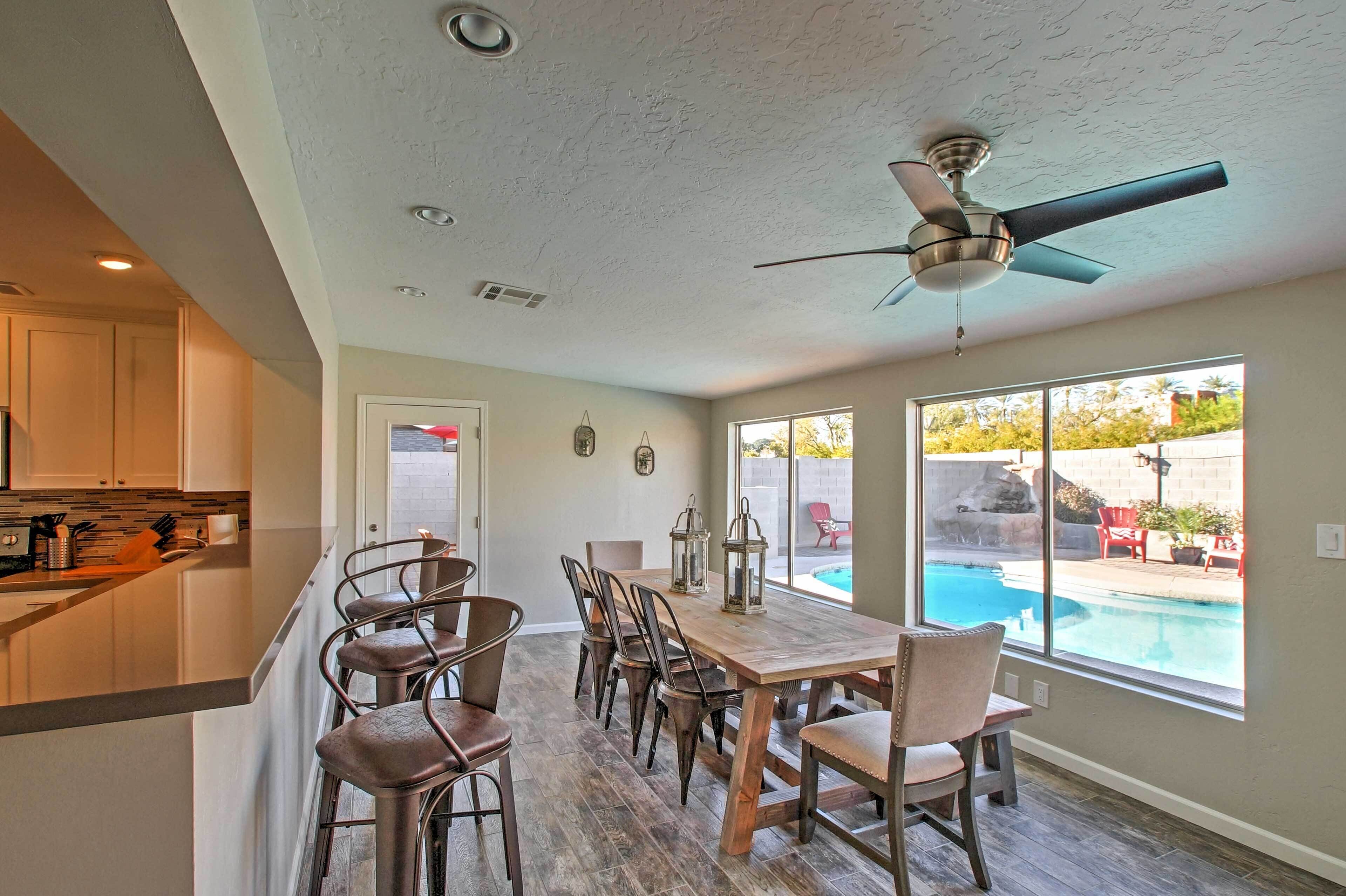 Una cocina con barra, mesa de comedor y sillas, y vista a una piscina.