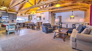 A spacious living area with a kitchen, wooden ceiling beams, and a cozy seating arrangement.