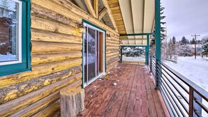 A log cabin with a wooden deck and a covered porch.