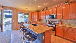 A kitchen with wooden cabinets, a granite countertop, a stainless steel refrigerator, and a built-in oven. - Arizona Retreat w/ Heated Pool, Fire Pit & Grill! (Surprise)