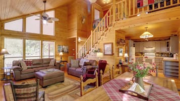 A spacious log cabin interior with a living room, dining area, and kitchen.