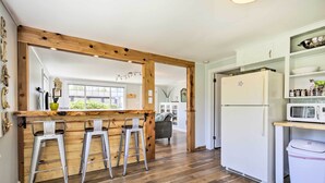 A kitchen with wooden bar stools, a white refrigerator, and a microwave.