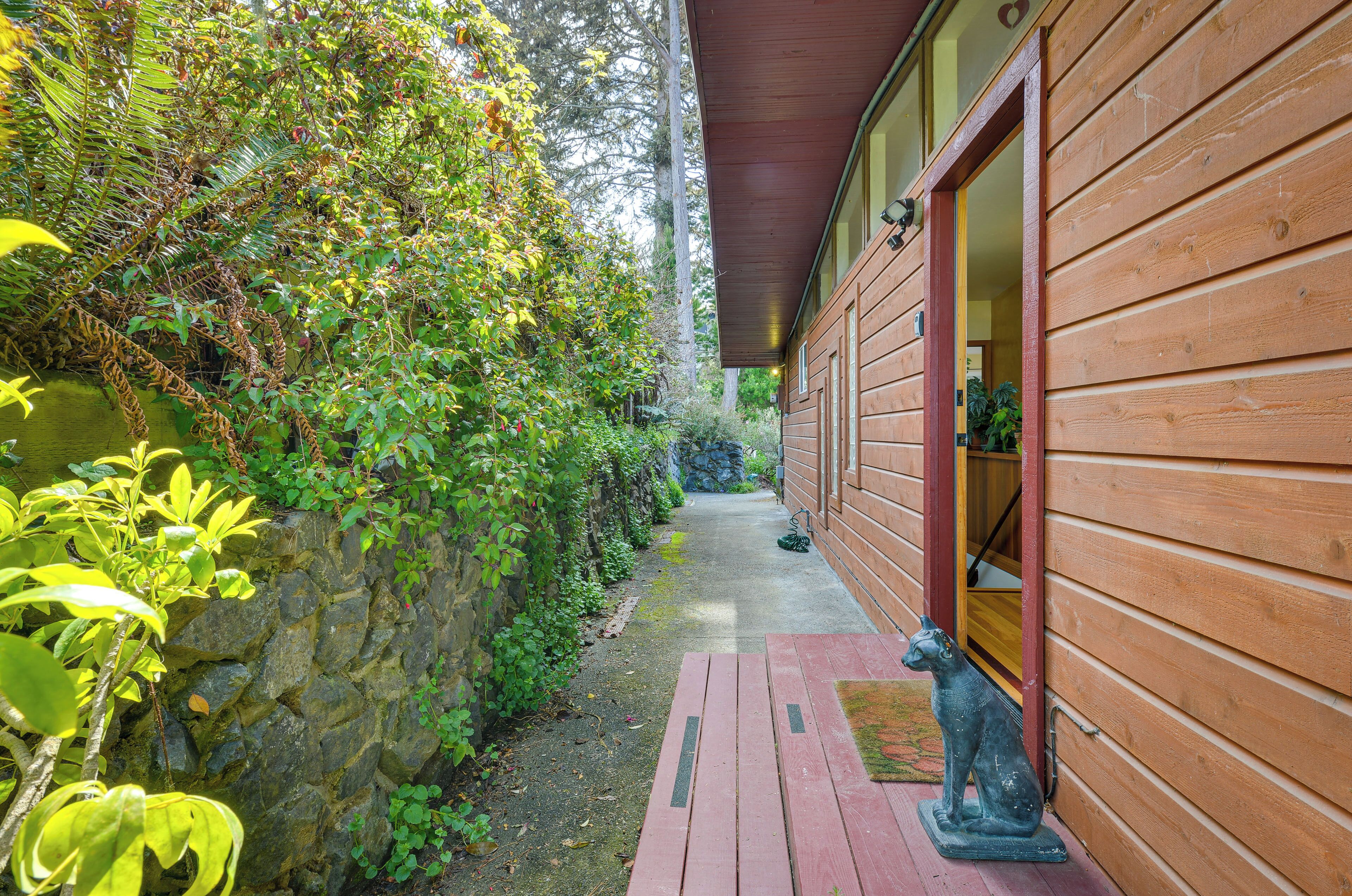 A wooden cabin with a stone wall and a wooden deck leading to the entrance.