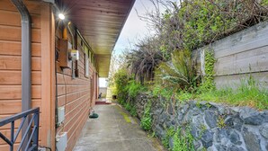A wooden building with a stone retaining wall, a concrete pathway, and a metal railing. - Mckinleyville Getaway w/ Hot Tub & Ocean Views! (McKinleyville)
