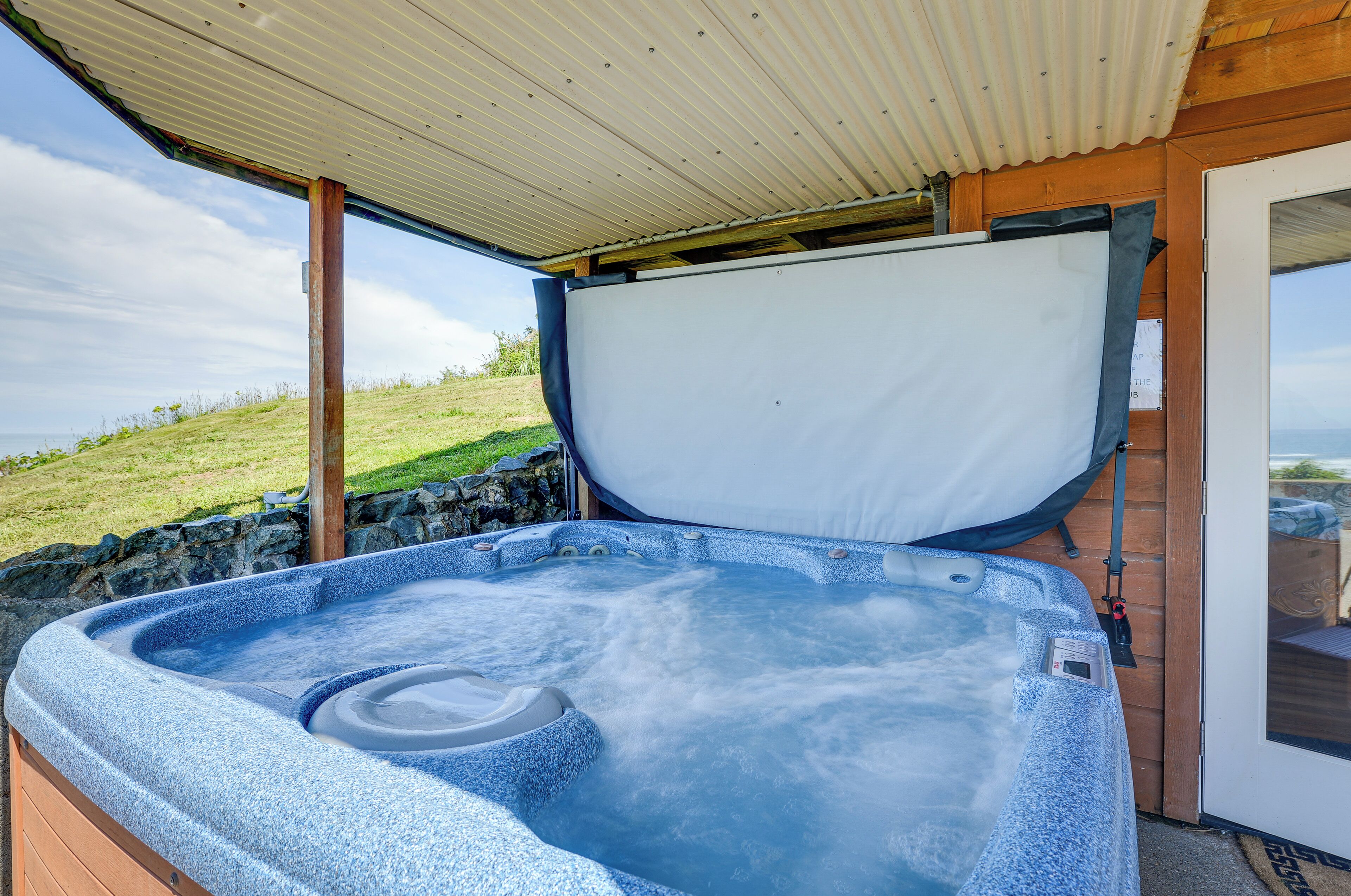 A hot tub with a wooden deck and a view of the landscape.