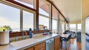 A kitchen with a large window, wooden cabinets, a dishwasher, and a dining area with chairs and a table. - Mckinleyville Getaway w/ Hot Tub & Ocean Views! (McKinleyville)