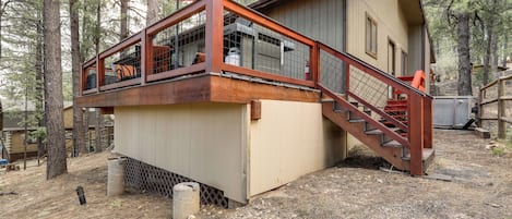 A cabin with a wooden deck and a staircase leading to a second floor.
