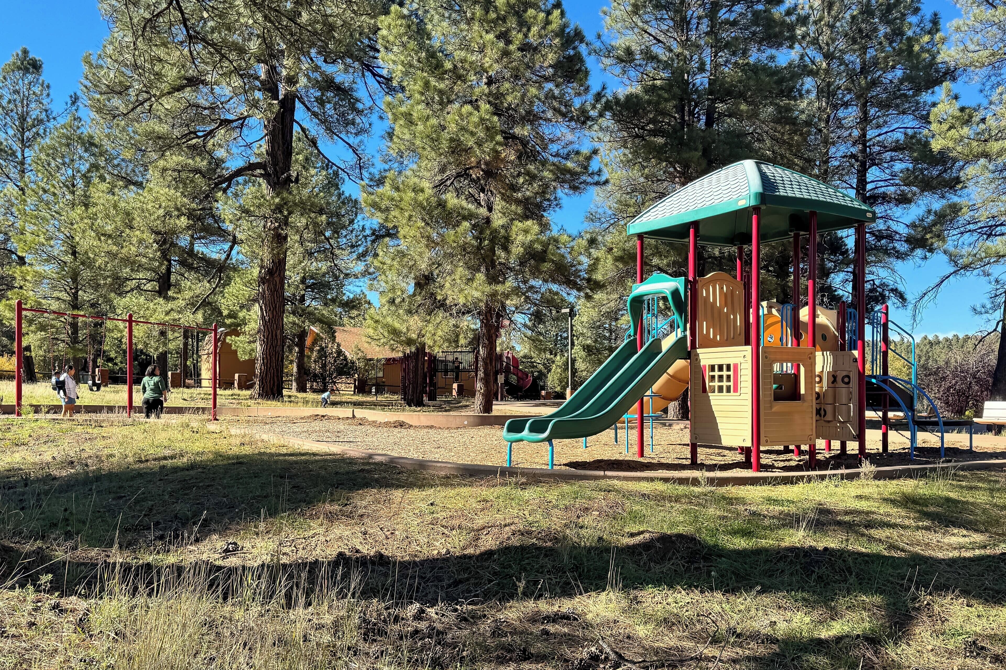 A playground with a green slide and a yellow playhouse.