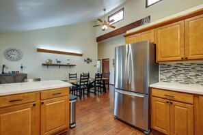 A kitchen with wooden cabinets, a stainless steel refrigerator, a dining table with chairs, and a ceiling fan. - 10 Mi to Downtown Flagstaff: Home w/ EV Charger (Flagstaff)