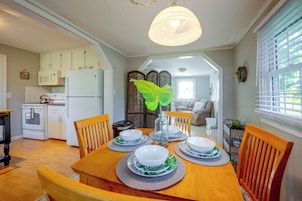 Un comedor con una mesa de madera preparada para cuatro personas, rodeada de sillas.