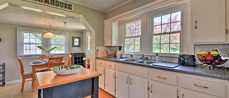 A kitchen with white cabinets, a wooden table, and a farmhouse sign.