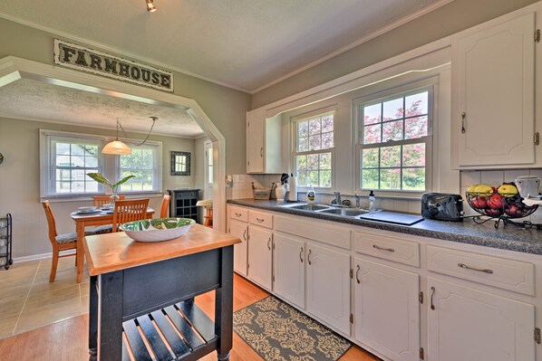 A kitchen with white cabinets, a wooden table, and a farmhouse sign. - Peaceful Elkin Vacation Rental ~ 17 Mi to Mt Airy! (Elkin)