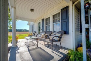 A covered porch with outdoor furniture, a clear view of the surrounding landscape, and a brick wall on one side.