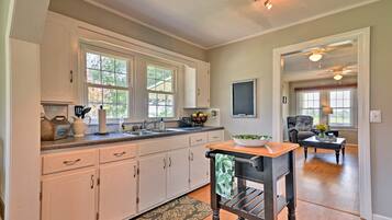 A kitchen with white cabinets, a wooden dining table, and a black chair.