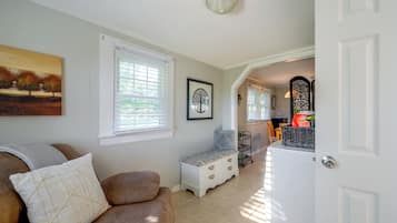 A living room with a brown sofa, a white door, and a hallway leading to another room.