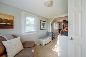 Uma sala de estar com um sofá marrom, uma porta branca e um corredor que dá para outro quarto.